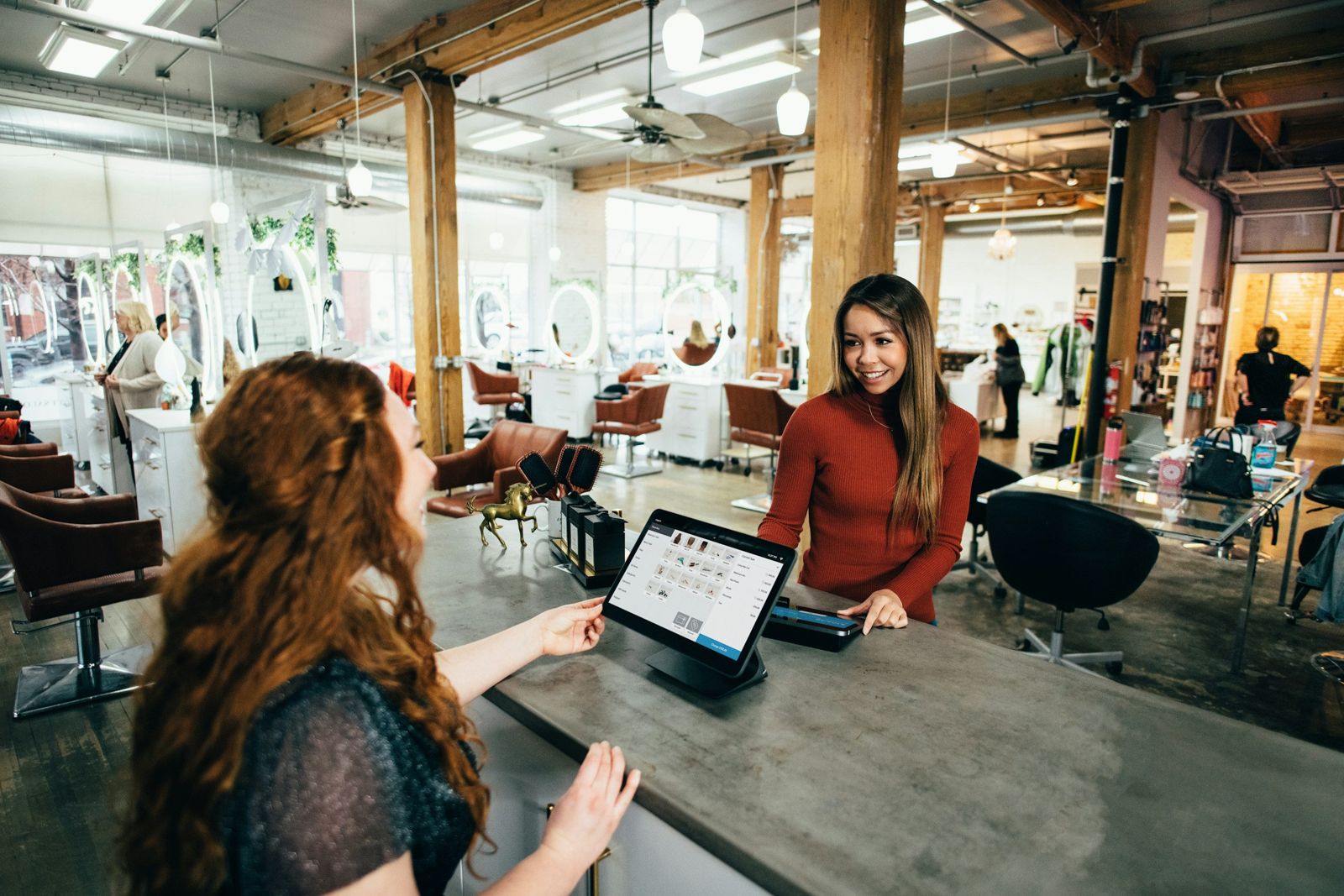 A salon owner checking in a customer at the front desk